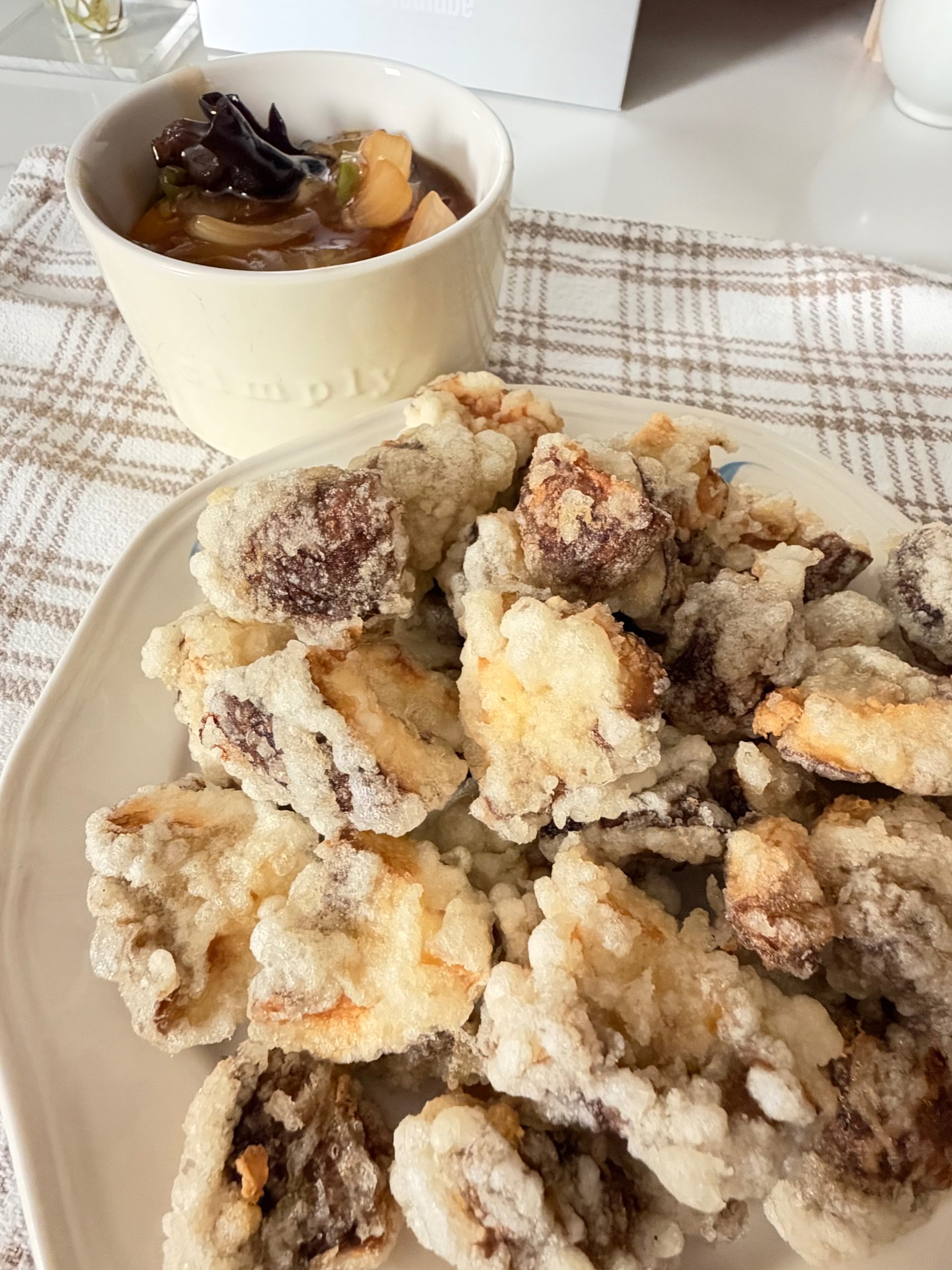 Crispy battered mushrooms on a plate with a bowl of sweet and sour dipping sauce.
