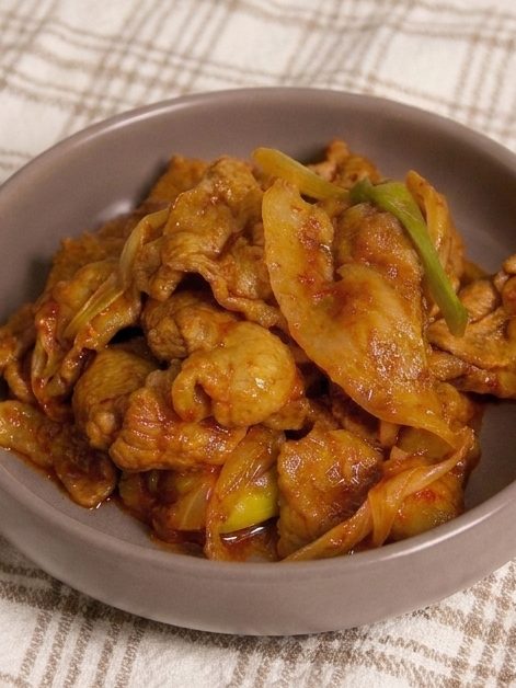 A bowl of Korean spicy pork stir-fry with green onions and onions.